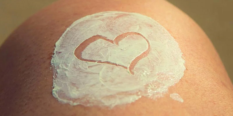 Knee with smear of skin cream with heart drawn in it