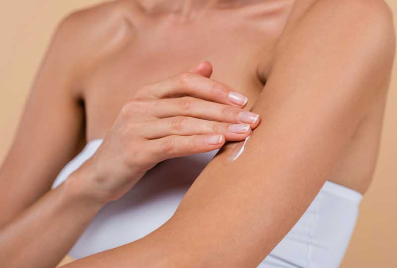 woman rubbing lotion into her arm.