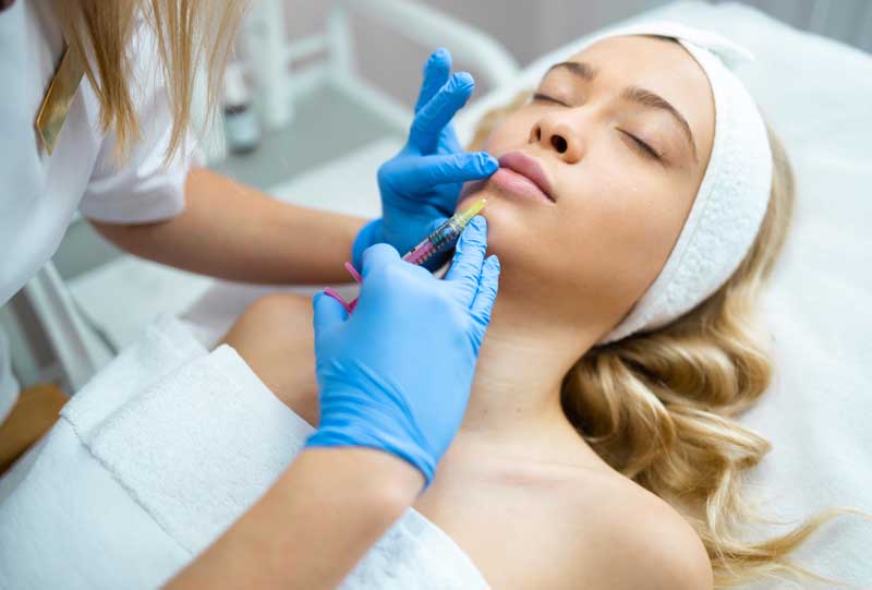 A woman getting a dermal filler injection in her chin